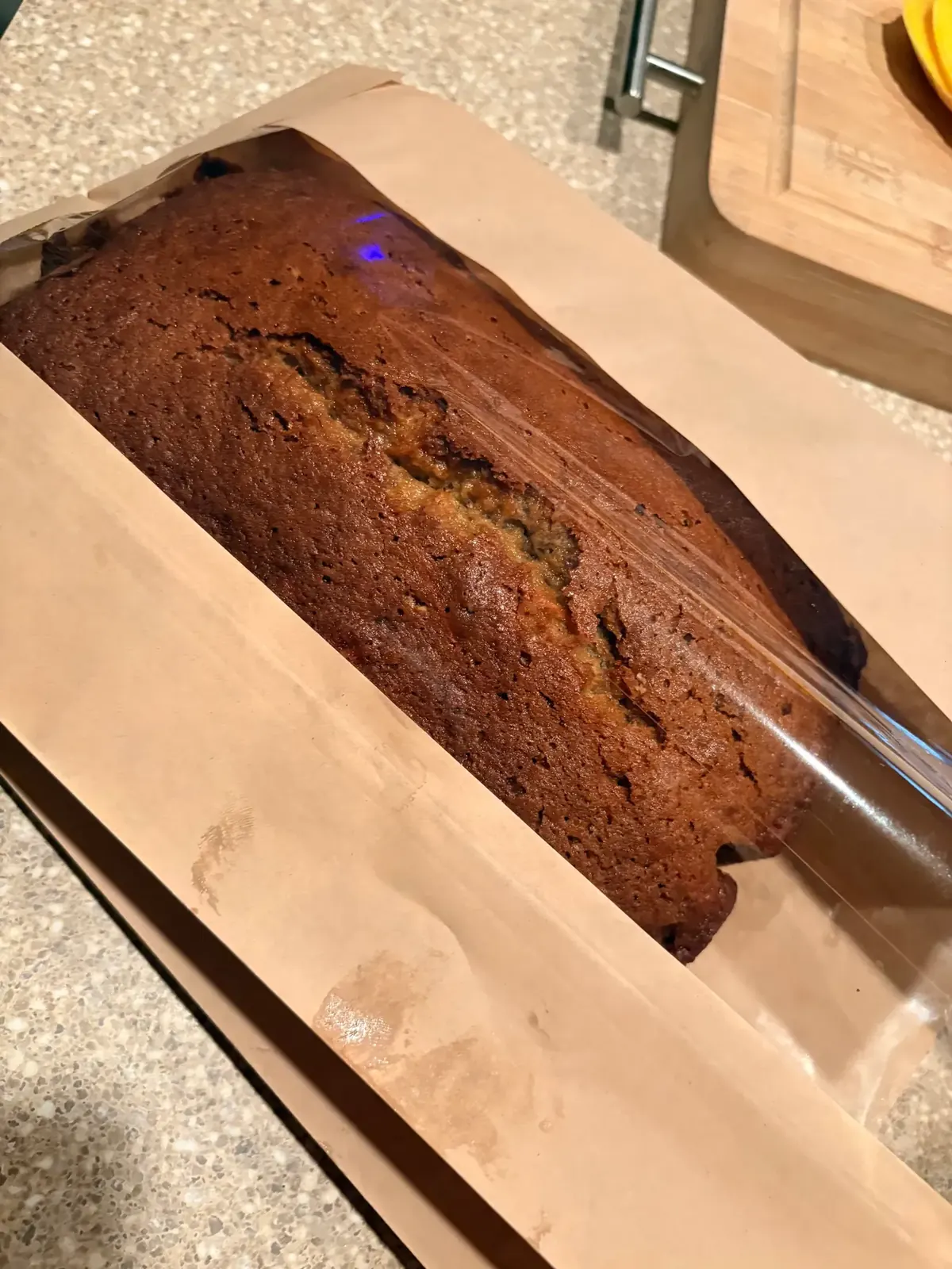 Loaf of homemade banana bread wrapped in a brown paper sleeve
