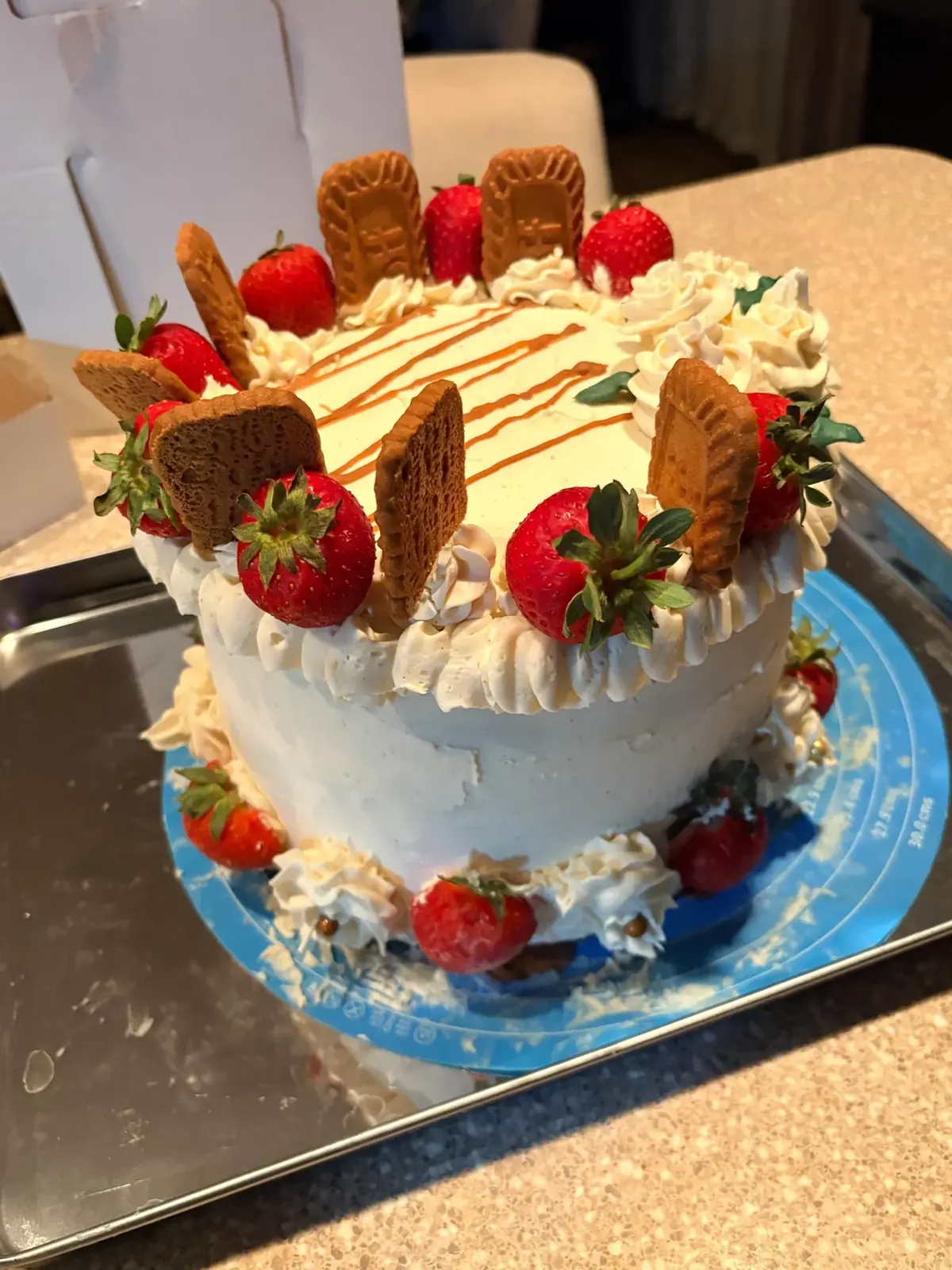 Layer cake topped with Biscoff cookies, strawberries and caramel drizzle
