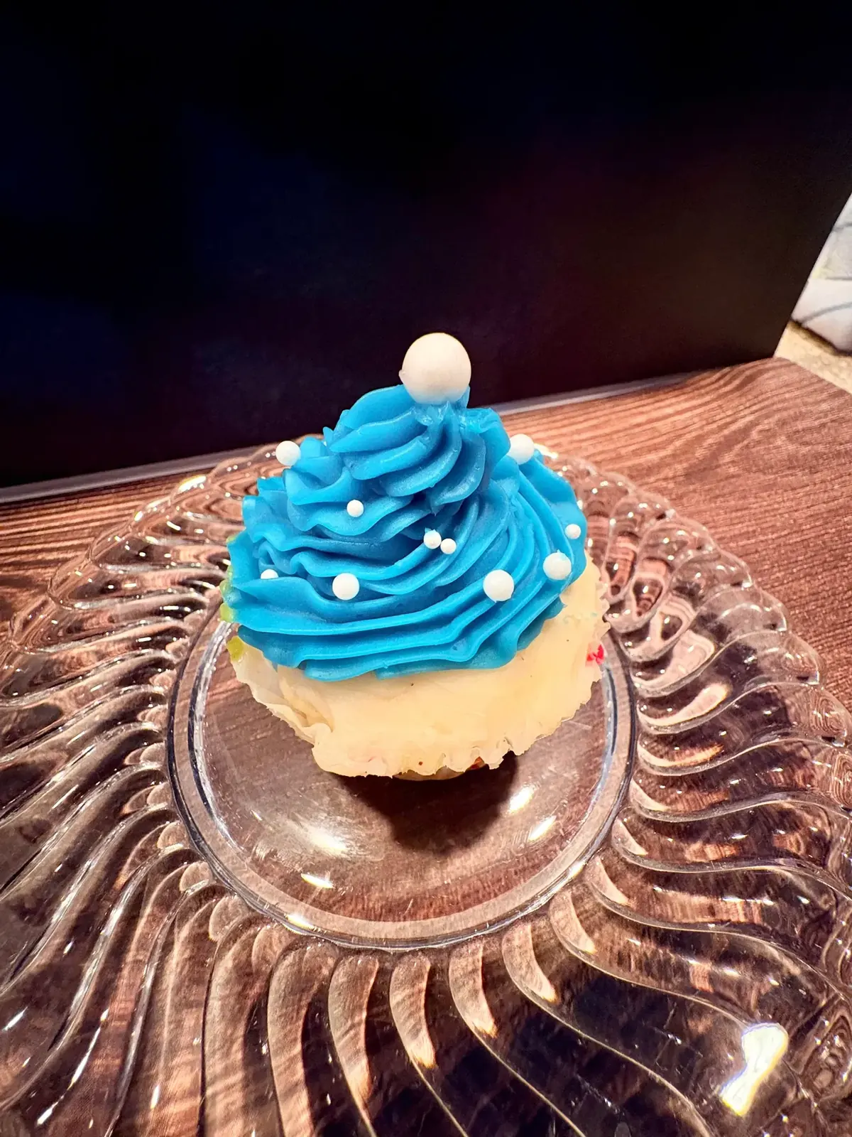 Cupcake with a tall blue buttercream swirl and a sugar pearl